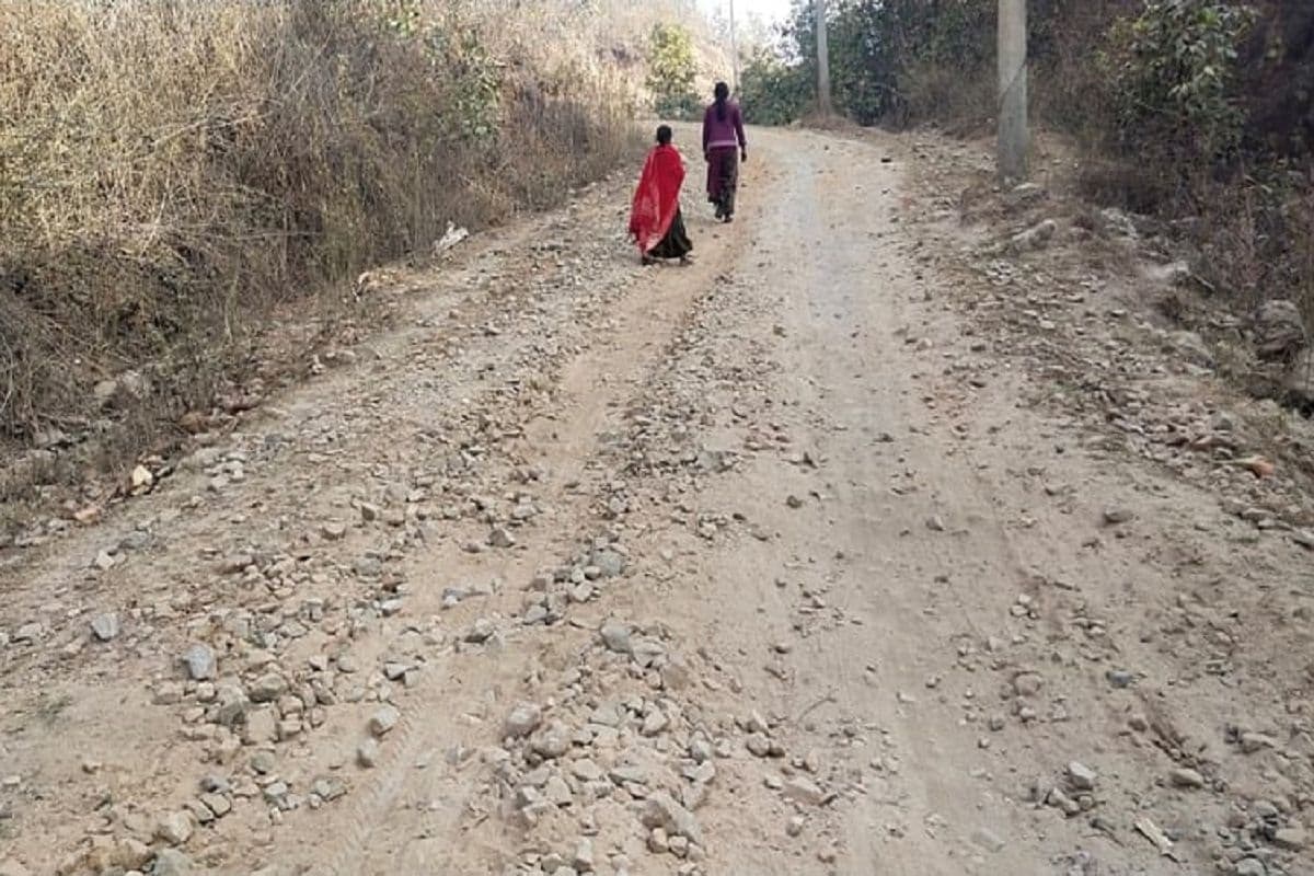 जर्जर सड़क से गुजरते स्थानीय लोग