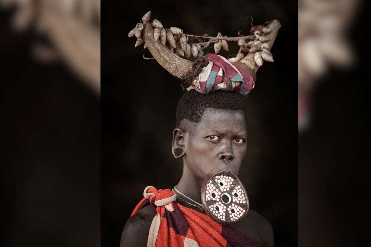 अपने होठों में प्लेट लगाए मुर्सी जनजाति की एक महिला. 