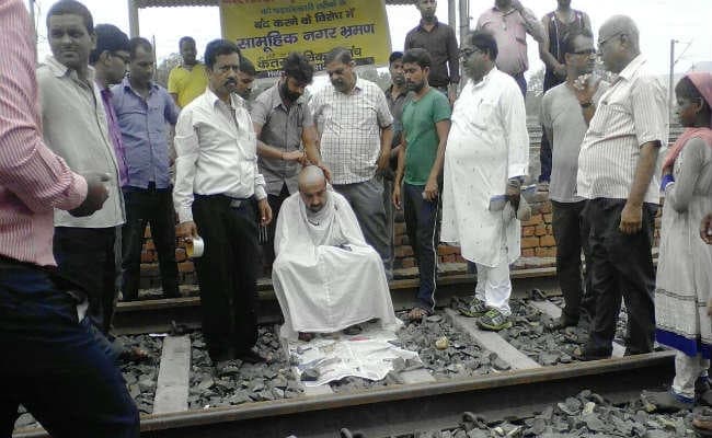 धनबाद-चंद्रपुरा रेल लाइन बंदी के विरोध में लोगों ने कराया सिर मुंडन
