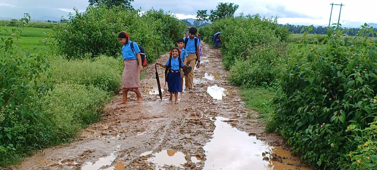 झारखंड : एक हाथ में चप्पल, दूसरे में छाता, पीठ पर बैग लेकर ऐसी जर्जर सड़क से स्कूल जाते हैं बच्चे