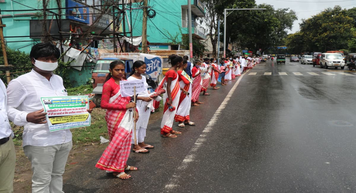Jharkhand News: अपनी मांगों को लेकर सड़क पर उतरे आदिवासी महिला-पुरुष, हाथों में तख्ती लिये बनाये मानव श्रृंखला