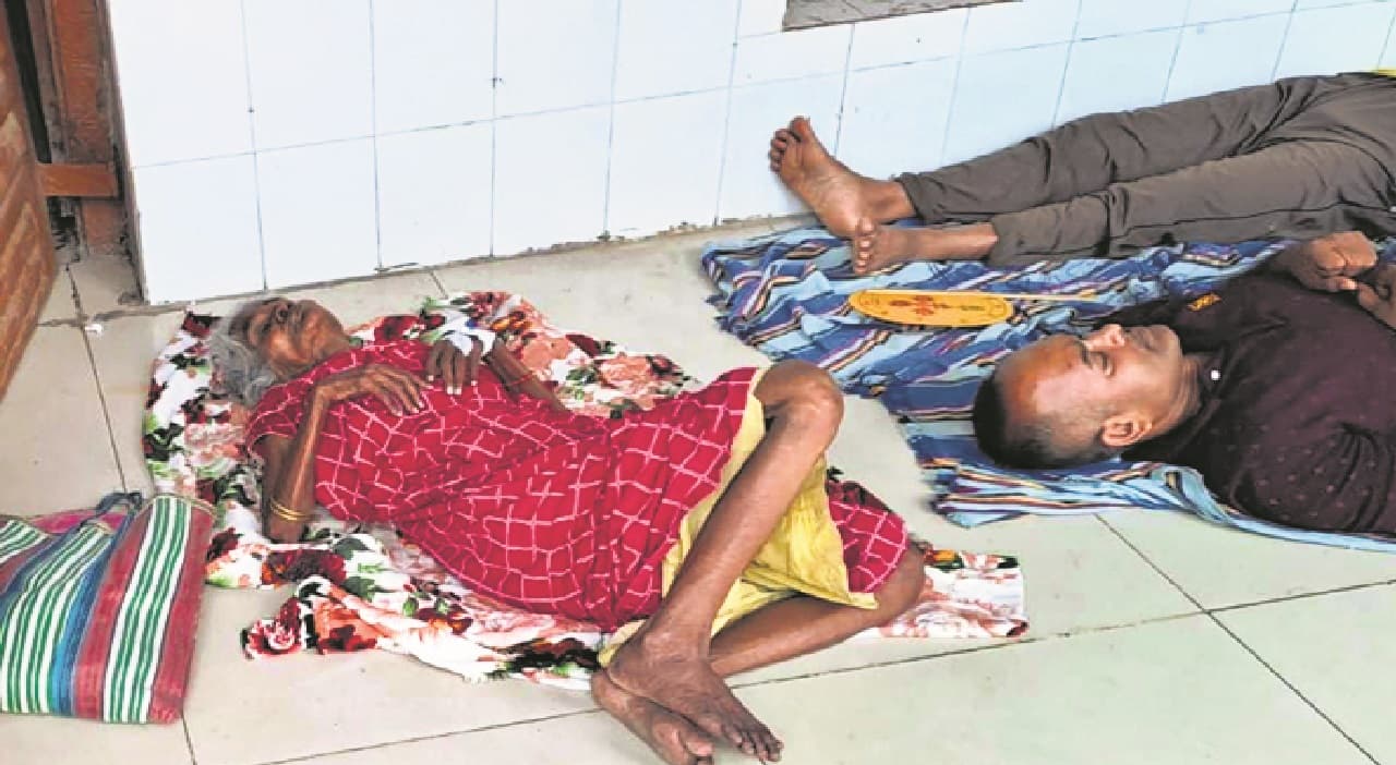 बदहाल स्वास्थ्य व्यवस्था : मुंगेर में बीमार बूढ़ी मां को गोद में लेकर घूमता रहा बेटा, बिस्तर नहीं मिला तो फर्श पर लिटाया