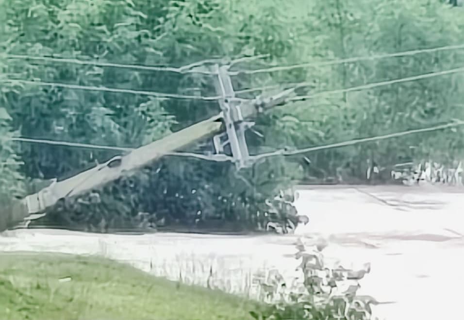 तार के सहारे बीच नदी में लटक रहा बिजली पोल