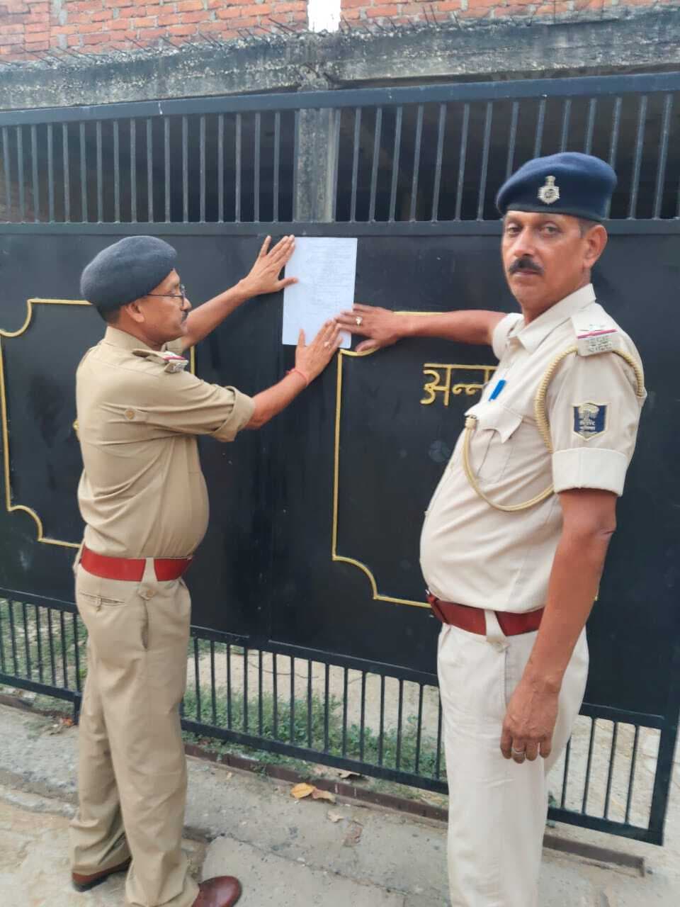 दो आरोपितों के घर पुलिस ने चिपकाया इश्तेहार