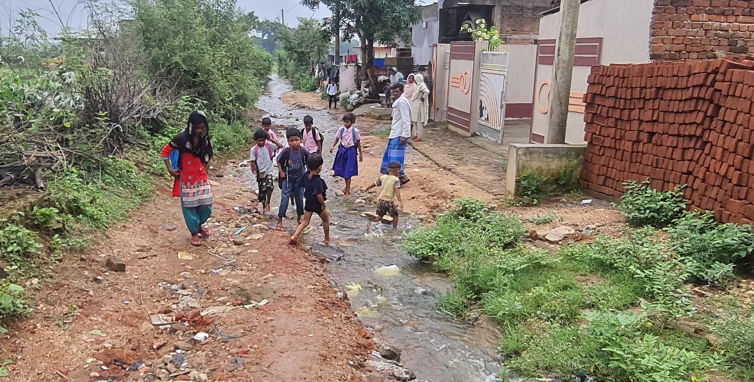 Bokaro News : सड़क पर बह रहे पानी से होकर स्कूल जाने को विवश हैं बच्चे