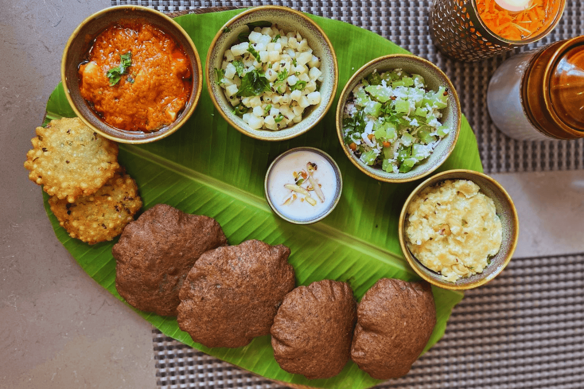 Ganesh Chaturthi Vrat Special Thali with 11 vrat-friendly dishes beautifully arranged on a traditional plate, including sabudana khichdi, aloo ki sabzi, kuttu puri, paneer curry, sweet kheer, fruits, and dry fruits, served as a festive fasting meal.