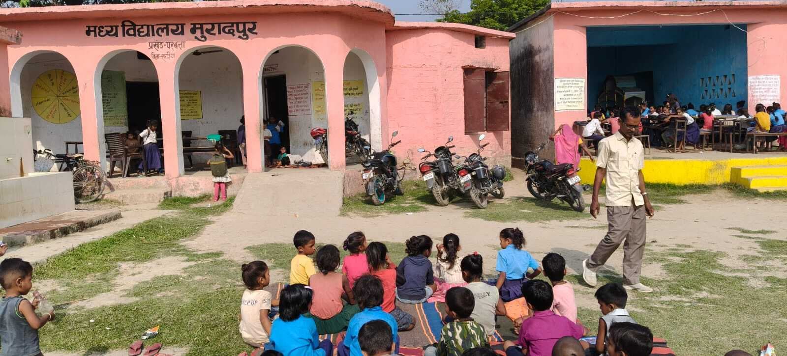 खुले आसमान के नीचे धूप और बरामदे में पढ़ने को विवश हैं स्कूली बच्चे