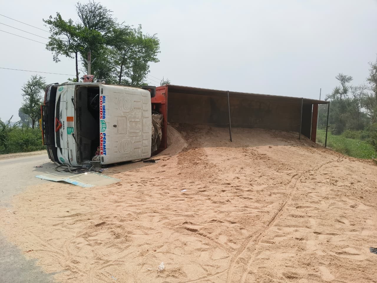 बालू लदा ट्रक अनियंत्रित होकर बीच सड़क पर पलटा, चालक घायल