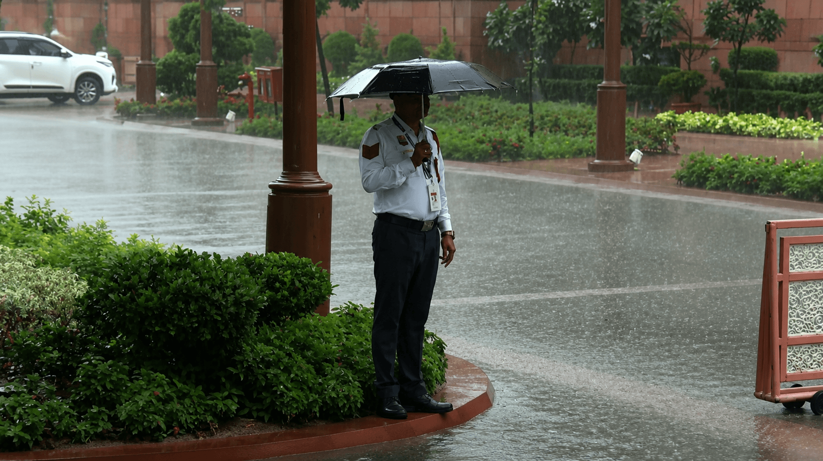 बारिश के बीच ड्यूटी करता सुरक्षाकर्मी