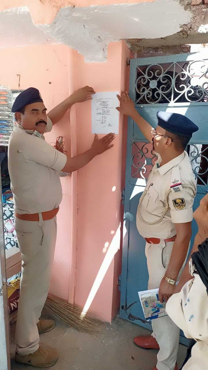 फरार वारंटी के घर पुलिस ने चिपकाया इश्तेहार