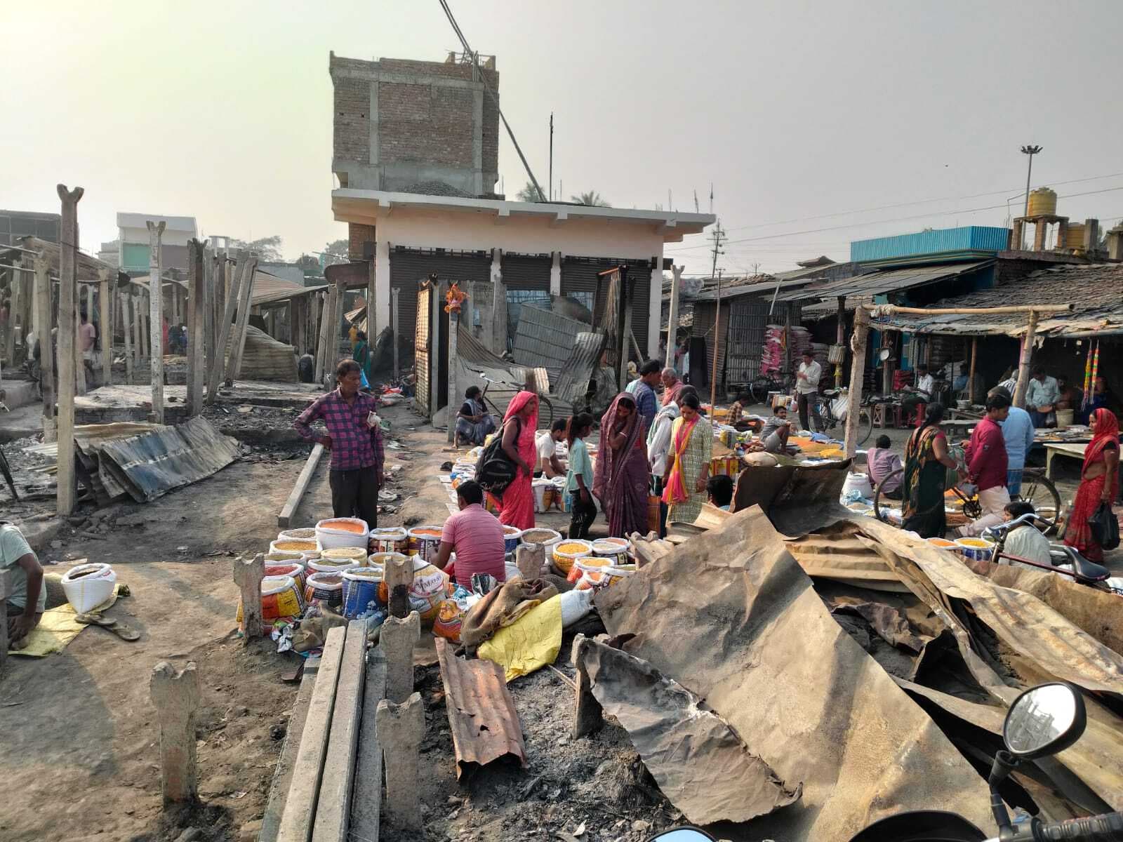 हाट में खुले आसमान के नीचे जले कचरे पर सजायी दुकानें