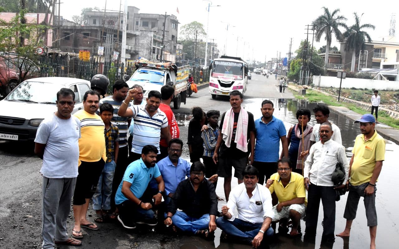 Dhanbad News: धैया की सड़क बन गयी तालाब, नाला के पानी में बैठकर लोगों ने दिया धरना