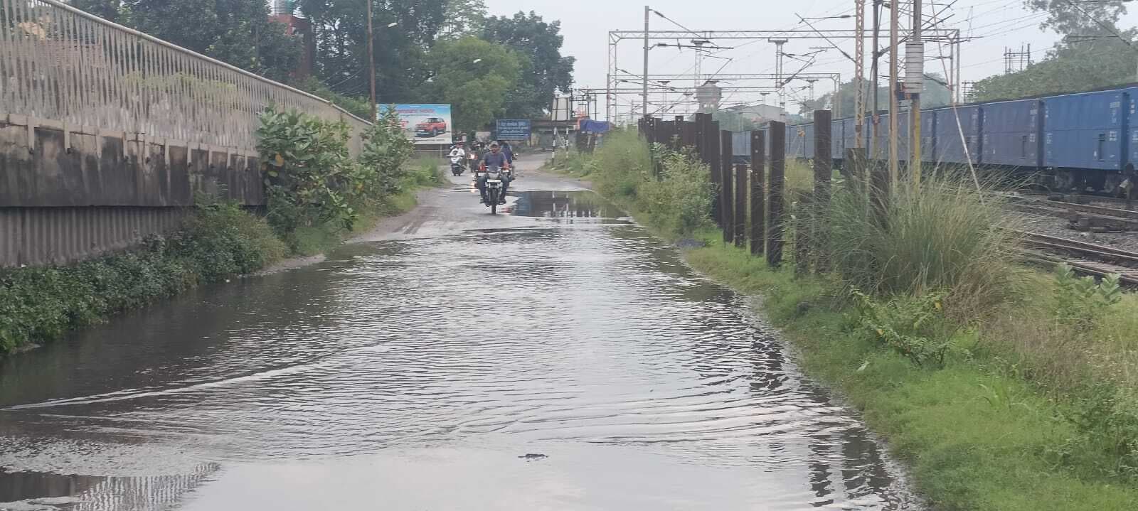 सड़क में जमे पानी की निकासी अपनी नाली से नहीं करने दे रहा रेलवे
