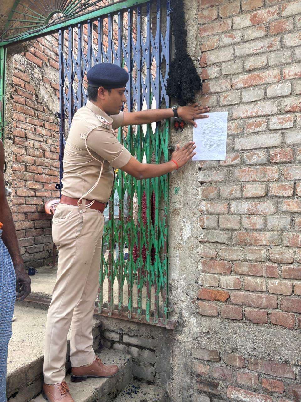 अभियुक्त के घर इश्तेहार चस्पा किया